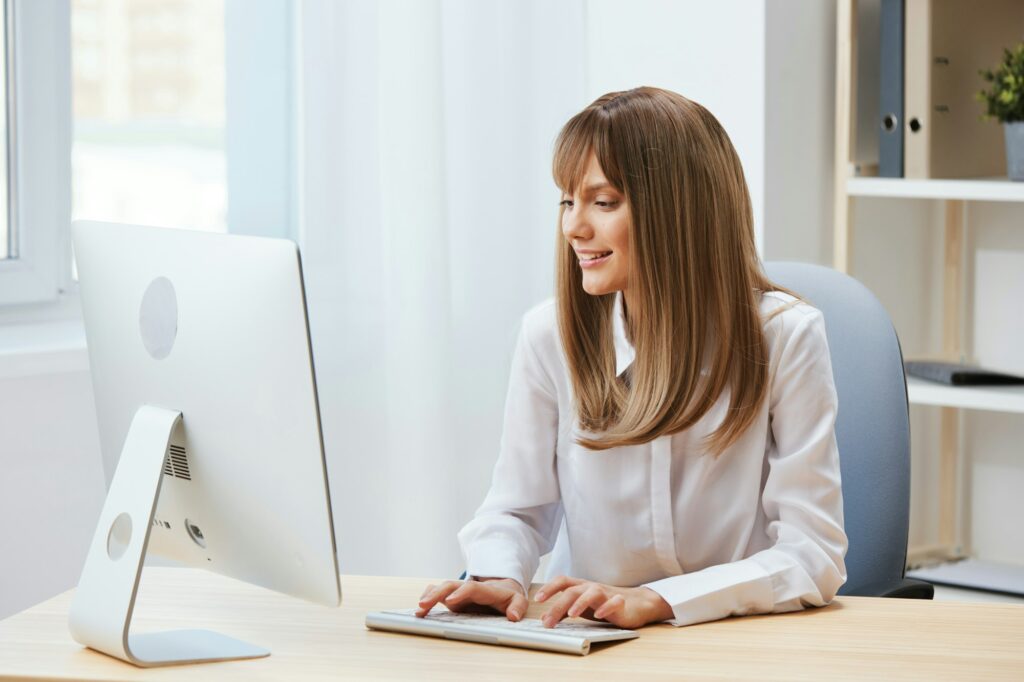 Cheerful happy adorable blonde businesswoman worker freelancer look at screen work on desktop